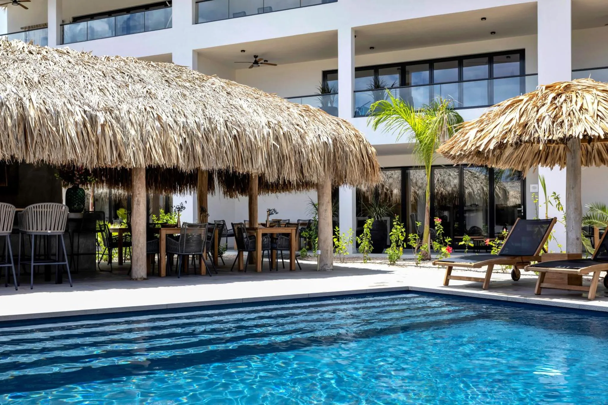 Terrasse ombragée avec mobilier de détente et piscine turquoise.