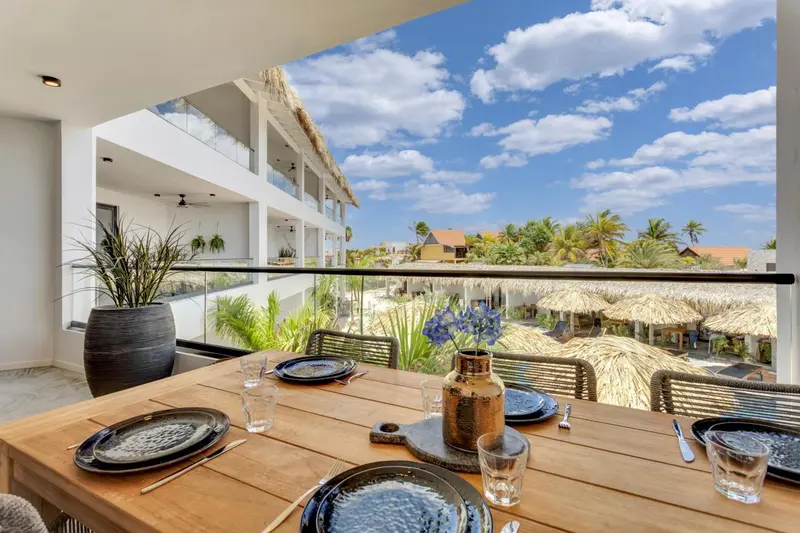 Table dressée sur une terrasse avec vue sur la végétation et le ciel nuageux.
