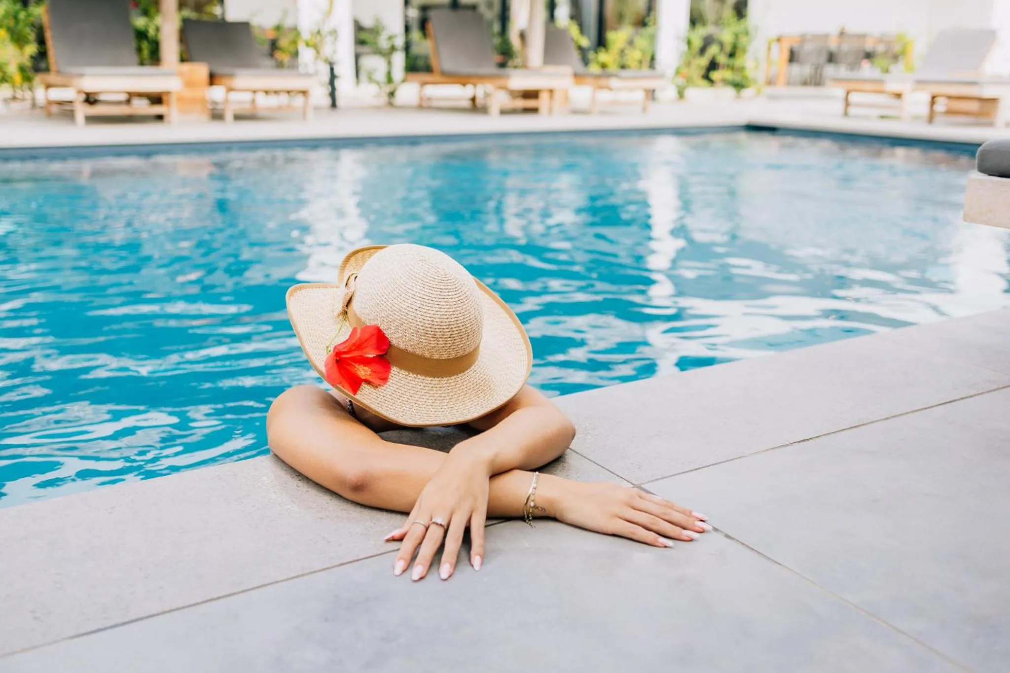 Une personne se détend au bord d'une piscine ensoleillée.