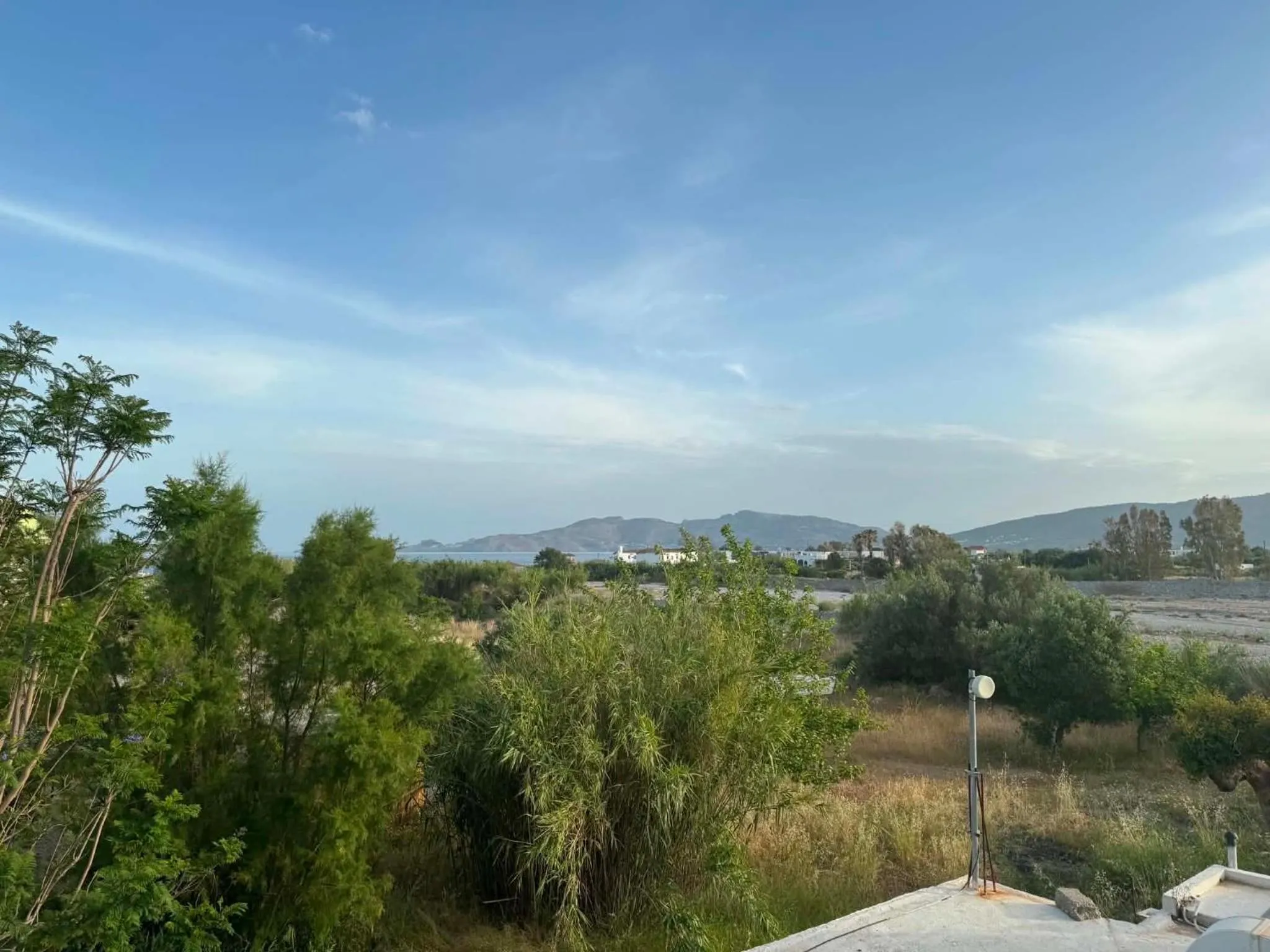 Vue d'ensemble sur un paysage montagneux et la mer depuis une végétation luxuriante.