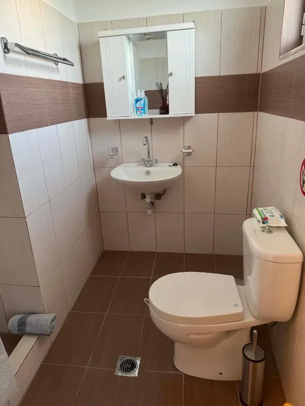 Une salle de bain carrelée avec lavabo, miroir et toilettes.