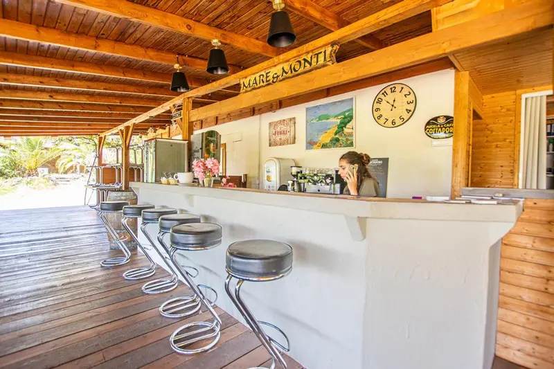Un comptoir de bar en bois avec des tabourets hauts et une personne assise.
