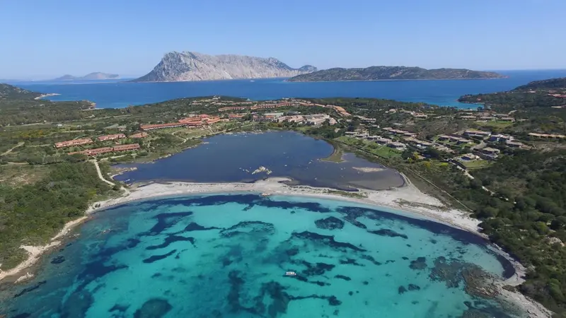 Vue aérienne d'une plage de sable blanc bordée d'une eau turquoise et d'une végétation luxuriante.