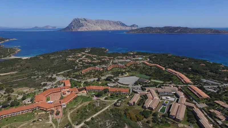 Vue aérienne d'un complexe hôtelier bordant une côte rocheuse et une mer turquoise.