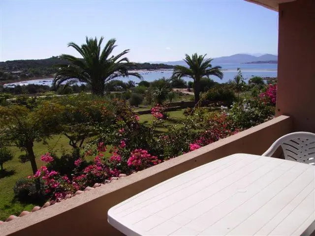 Terrasse fleurie donnant sur une vue mer et des collines verdoyantes.