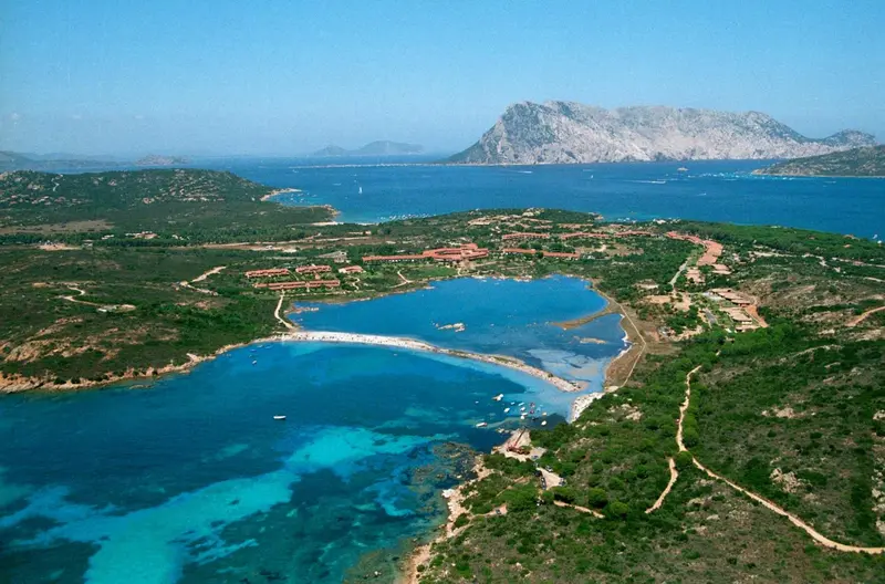 Vue aérienne d'une côte rocheuse et d'une baie turquoise bordée de végétation.