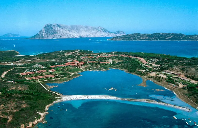 Vue aérienne d'une station balnéaire bordant une baie turquoise et une montagne.
