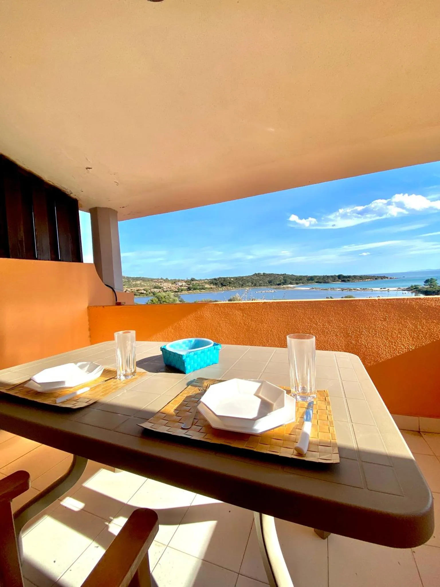 Table dressée sur une terrasse ensoleillée avec vue sur la mer et la côte.