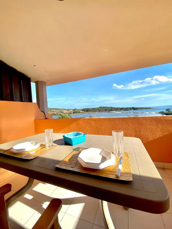 Table dressée sur une terrasse ensoleillée avec vue sur la mer et la côte.