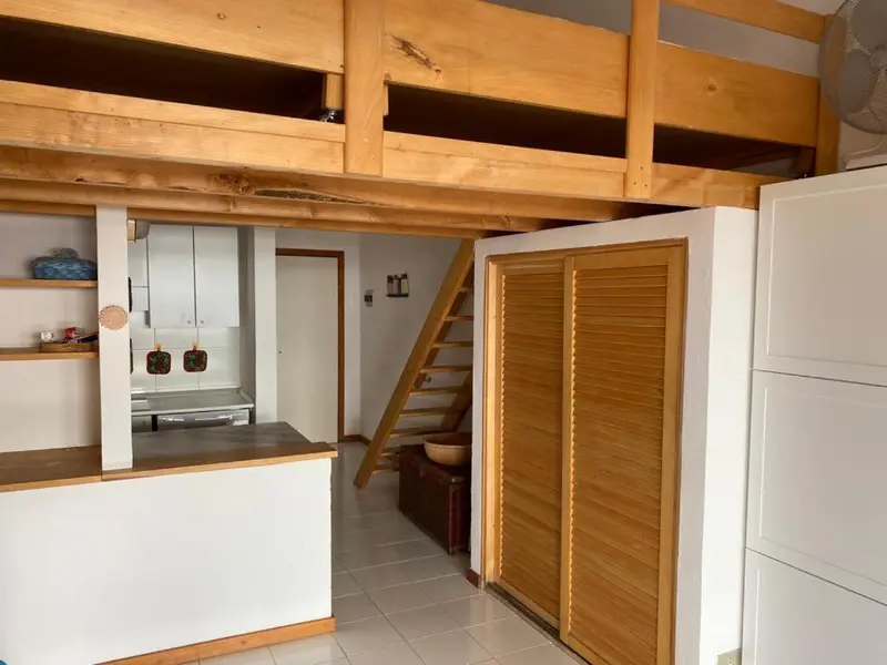Une chambre mansardée avec un escalier en bois et une kitchenette ouverte.
