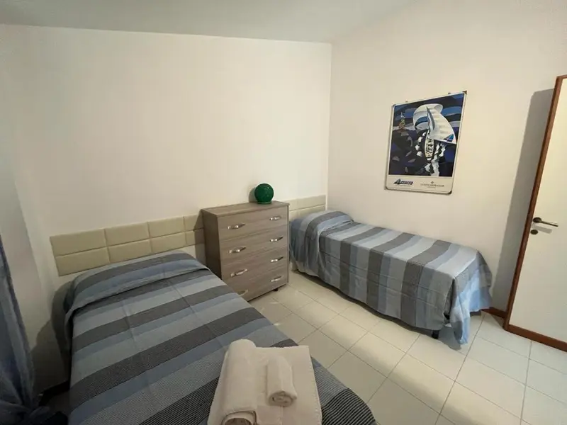 Une chambre avec deux lits simples et une commode.