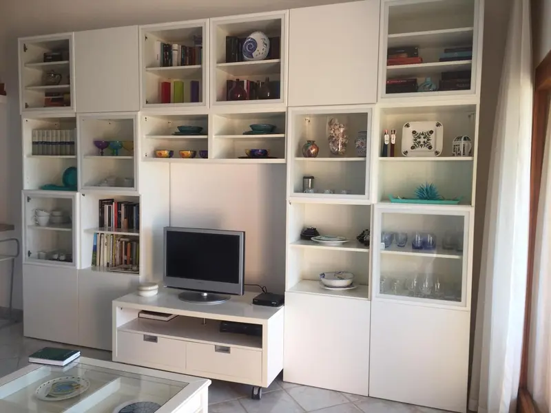 Bibliothèque blanche moderne avec objets décoratifs et un téléviseur.