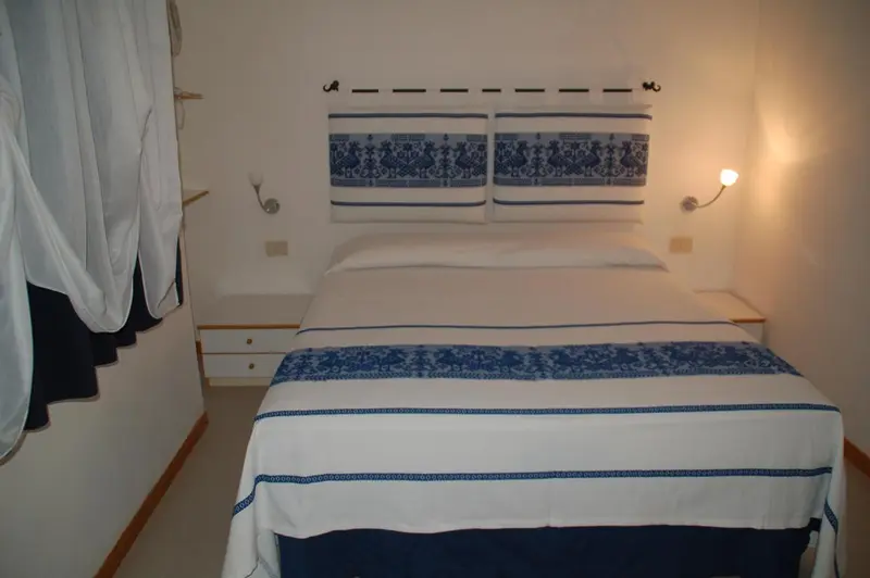 Une chambre lumineuse avec un lit double et des lampes de chevet.