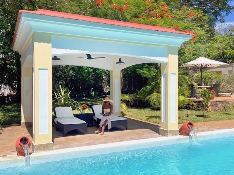 Un espace de détente ombragé avec des chaises longues près d'une piscine.