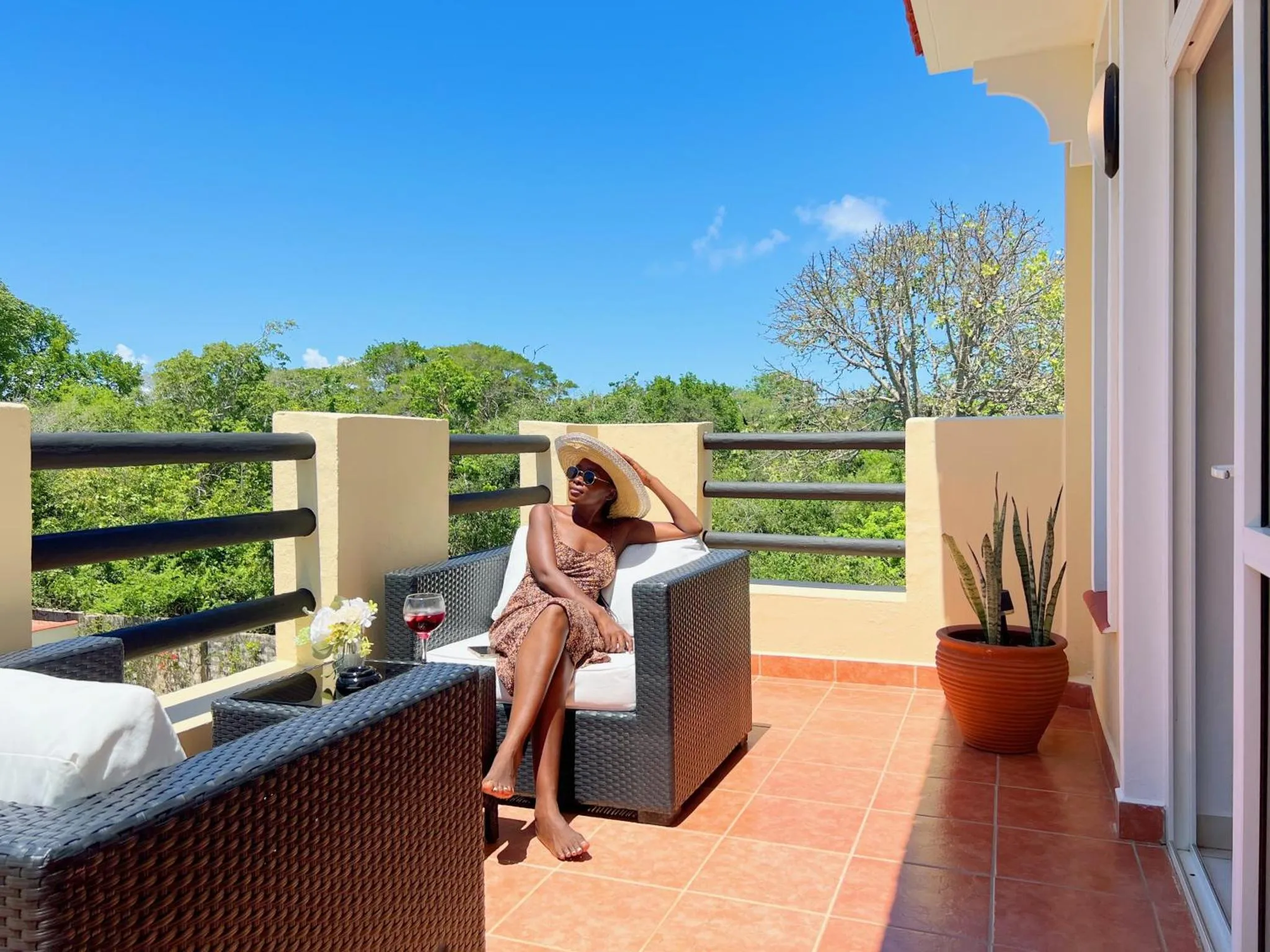Une personne se détend sur une terrasse ensoleillée avec vue sur la végétation.