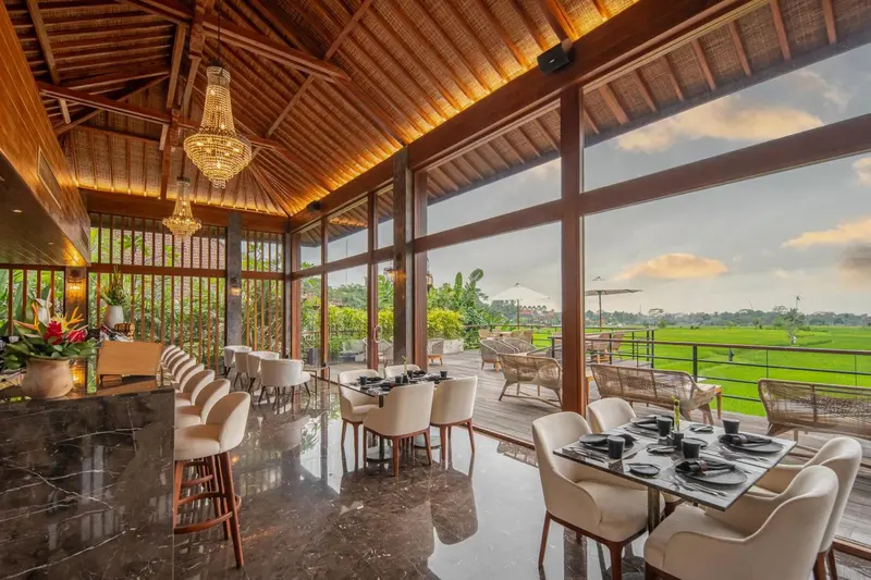 Une salle à manger lumineuse avec de grandes baies vitrées donnant sur une végétation luxuriante.