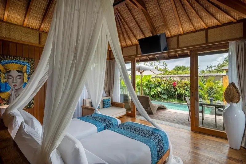Une chambre avec un lit à baldaquin donnant sur une piscine et une végétation luxuriante.