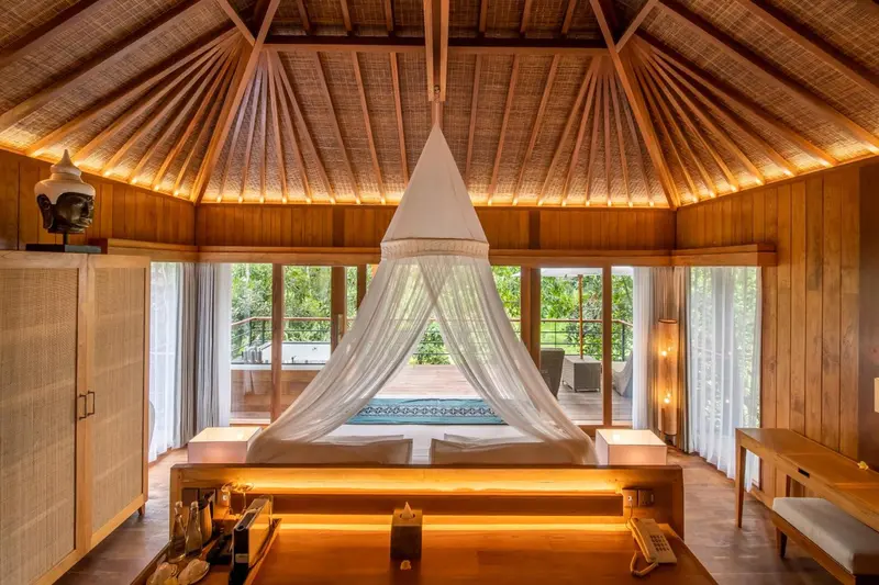 Une chambre lumineuse avec un lit à baldaquin et une vue sur l'extérieur.