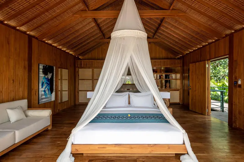 Une chambre lumineuse avec un grand lit à baldaquin et un canapé.