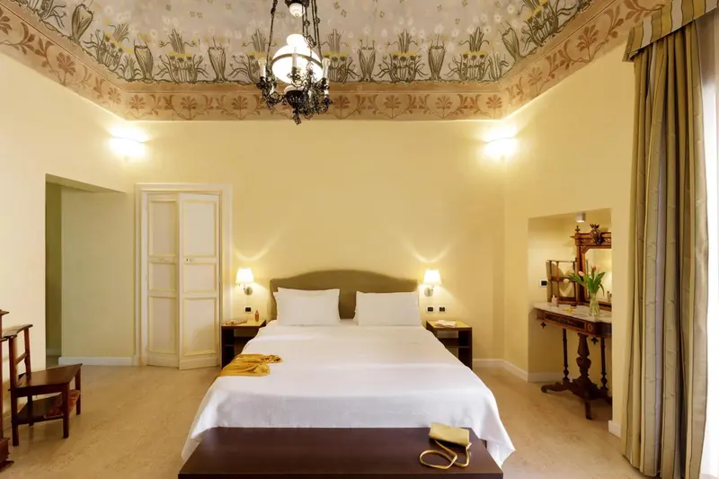 Une chambre lumineuse avec un grand lit et une décoration florale au plafond.