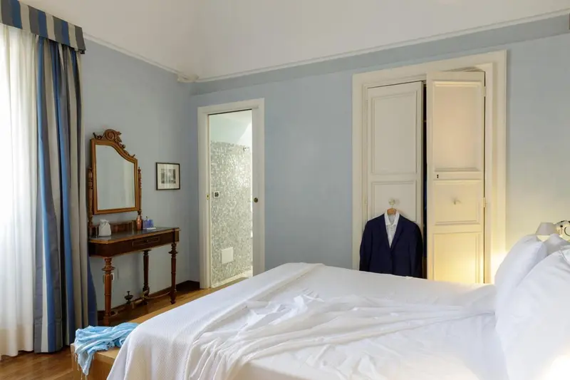 Une chambre lumineuse avec un lit recouvert d'une courtepointe blanche et un bureau coiffeuse.
