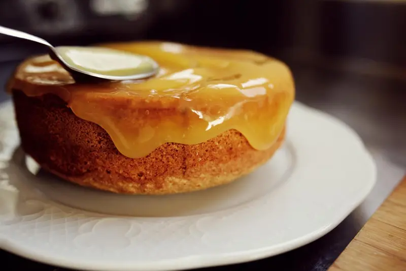 Un gâteau rond recouvert de glaçage caramel est présenté sur une assiette blanche.