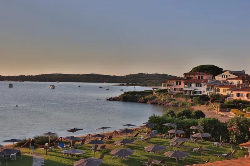 Vue d'un complexe hôtelier au bord de la mer avec une plage et des parasols.