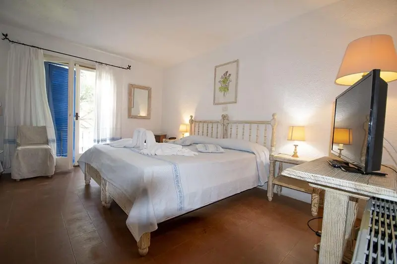 Chambre lumineuse avec un lit double et un accès à une terrasse.