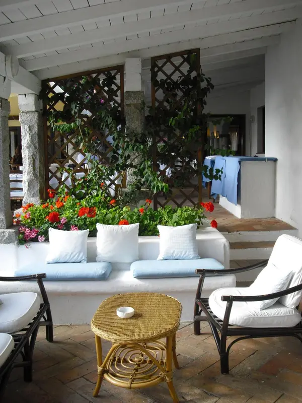 Espace de détente extérieur avec mobilier en rotin et végétation luxuriante.