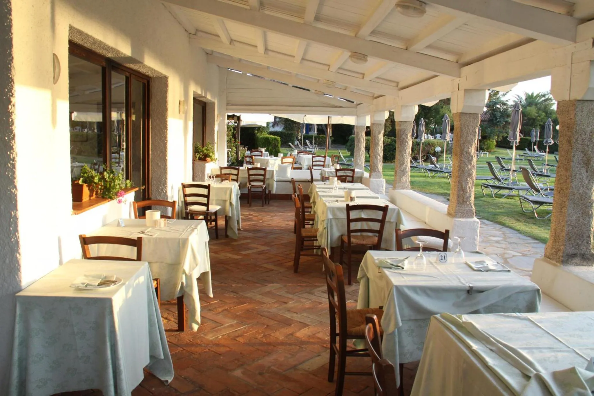 Terrasse ombragée avec tables dressées pour un repas en extérieur.