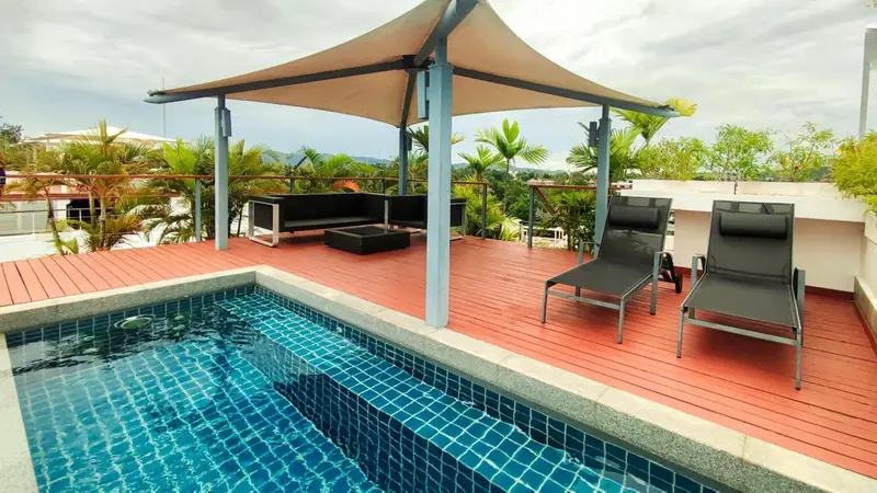 Terrasse avec piscine et mobilier de détente.