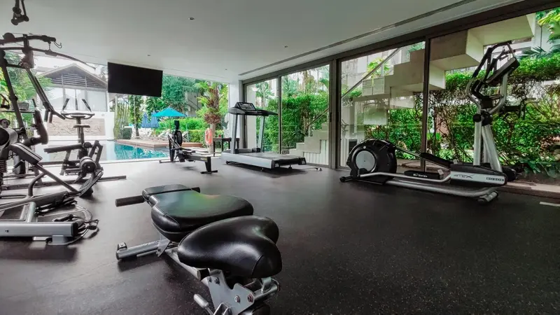 Une salle de sport lumineuse avec plusieurs appareils de musculation et vue sur une piscine.