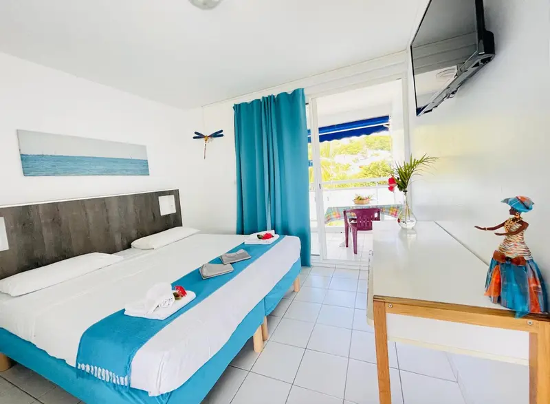 Une chambre lumineuse avec un lit double et un accès à une terrasse.