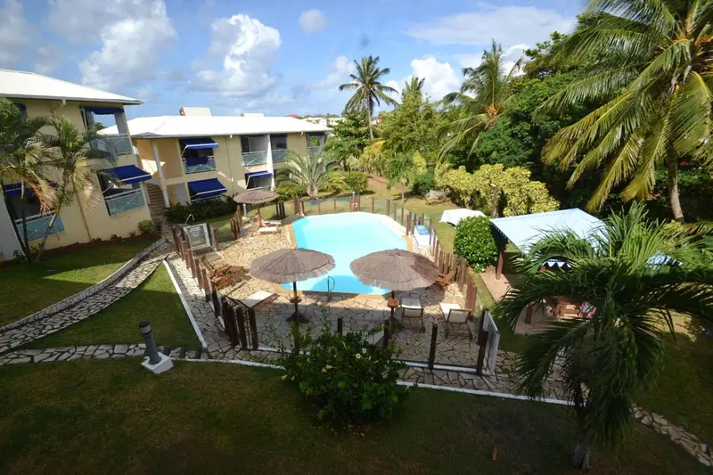 Vue aérienne d'un complexe hôtelier avec piscine et végétation tropicale.