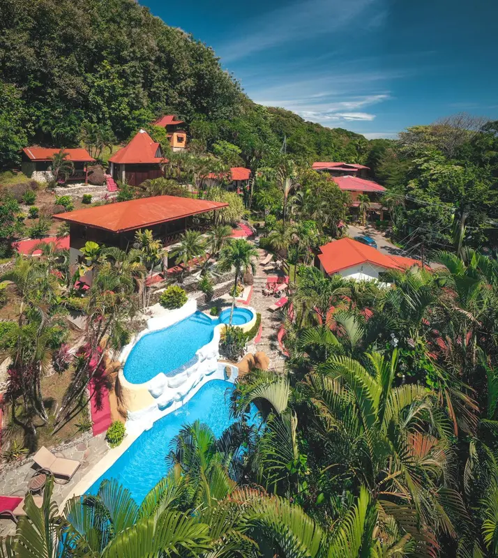 Vue aérienne d'un complexe hôtelier avec piscine et végétation luxuriante.
