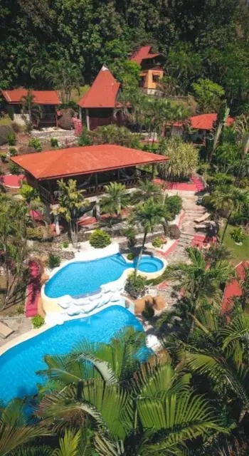 Vue aérienne d'un complexe hôtelier avec piscine et végétation tropicale.