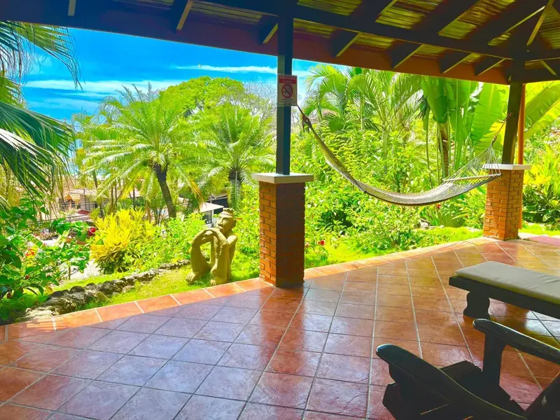 Terrasse carrelée avec un hamac et une vue sur une végétation luxuriante.