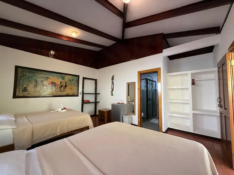Une chambre lumineuse avec deux lits simples et une salle de bain attenante.