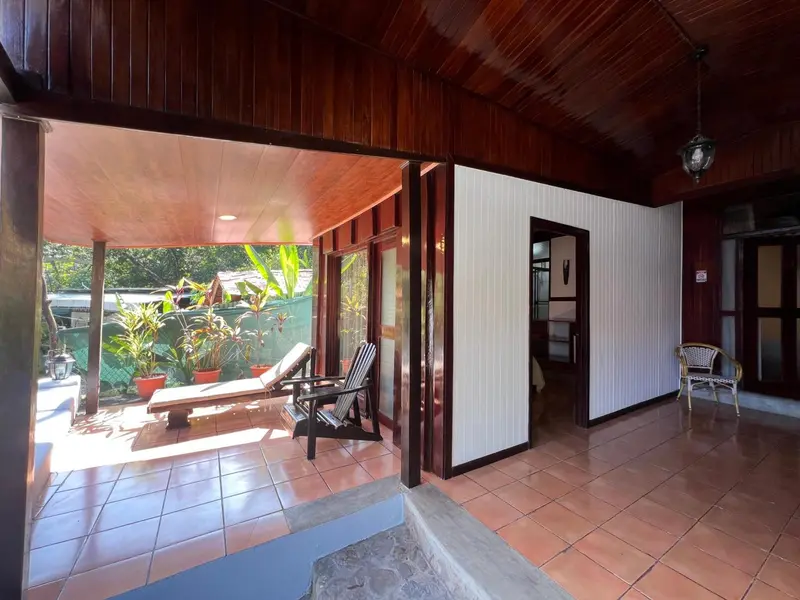 Terrasse ombragée avec mobilier de détente et accès à une pièce intérieure.