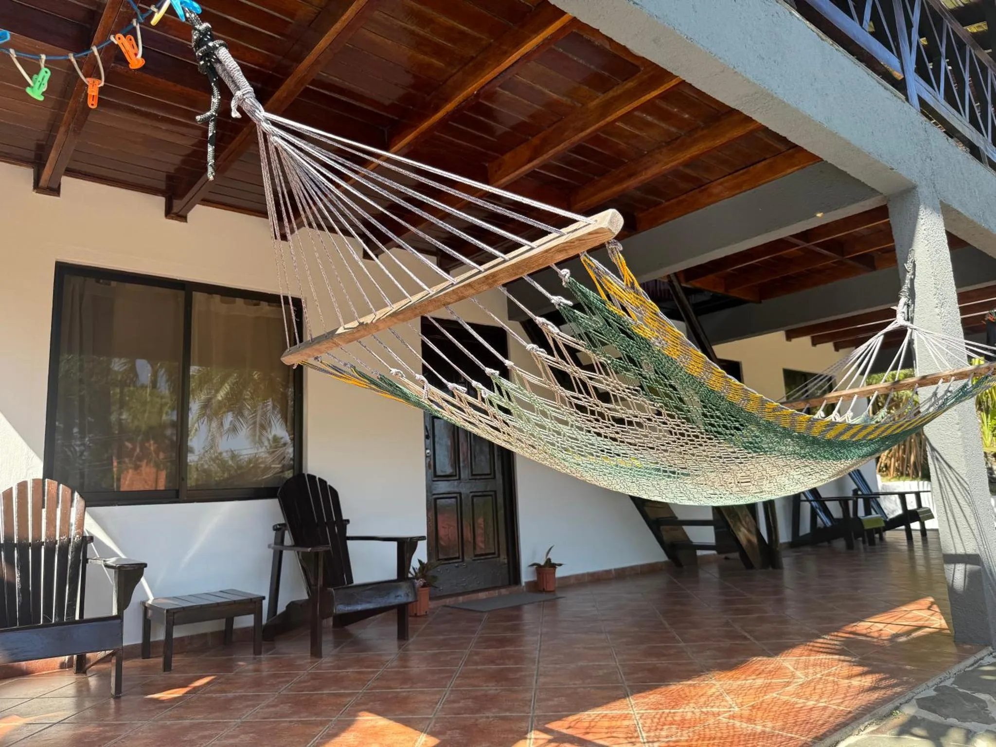 Un hamac coloré est suspendu sur une terrasse ombragée.