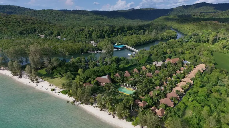 Vue aérienne d'un complexe hôtelier bordant une plage et une mangrove.