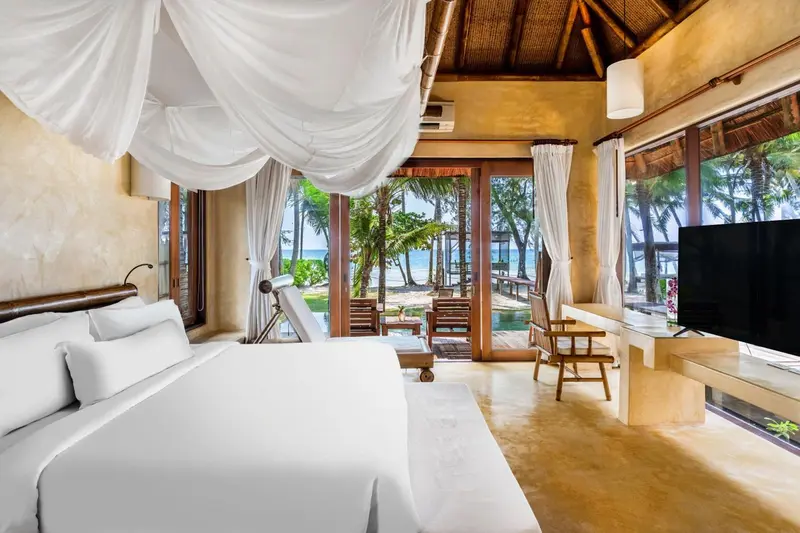 Une chambre lumineuse avec un lit à baldaquin donnant sur une plage.