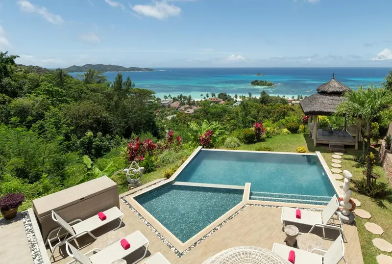 Une piscine à débordement offre une vue sur la végétation luxuriante et la mer turquoise.