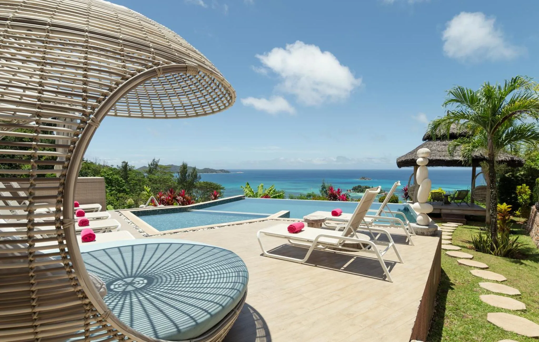 Transats et parasols ombragent une terrasse avec piscine et vue sur la mer.