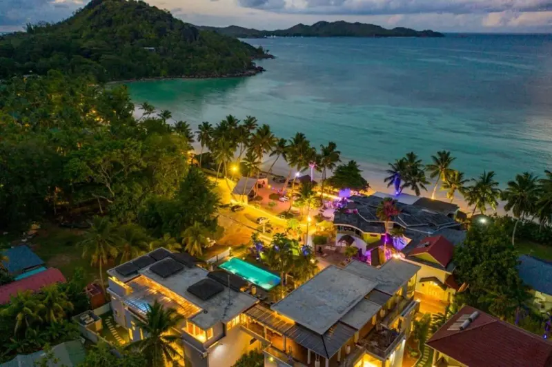 Vue aérienne d'un complexe hôtelier illuminé au bord d'une plage tropicale.
