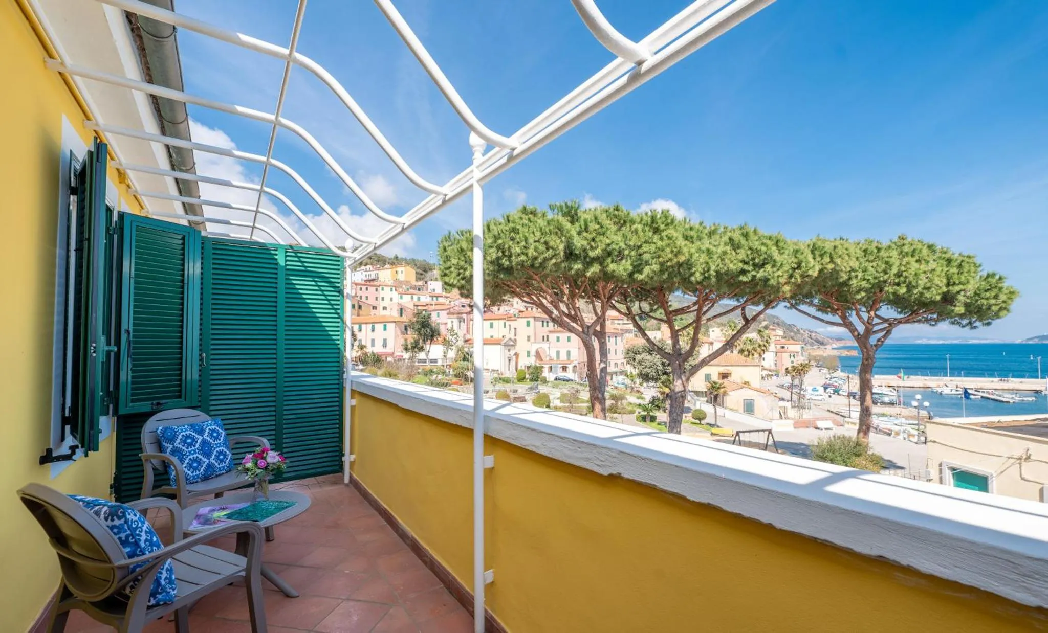 Terrasse ensoleillée avec mobilier d'extérieur et vue sur la mer et la ville.