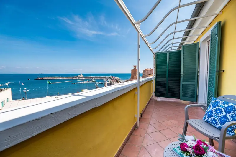 Balcon ensoleillé avec vue sur la mer et le port.