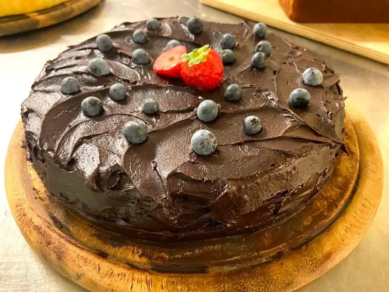 Un gâteau au chocolat décoré de myrtilles et d'une fraise.