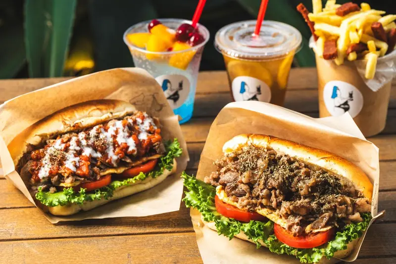 Assortiment de sandwichs et de boissons rafraîchissantes sur une table en bois.