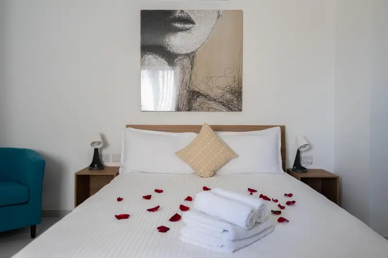 Une chambre avec un grand lit recouvert de pétales de fleurs et d'une décoration murale.